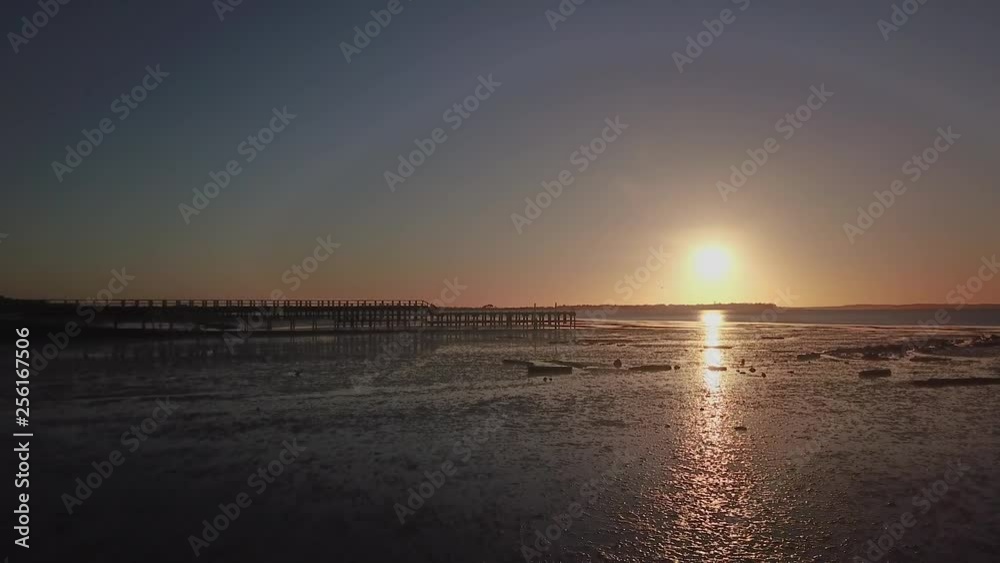 Aerial fly over a beach and jetty during sunset and low tide, starts low and rises up in altitude. Aerial fly over a beach and jetty during sunset and low tide, starts low and rises up in altitude.