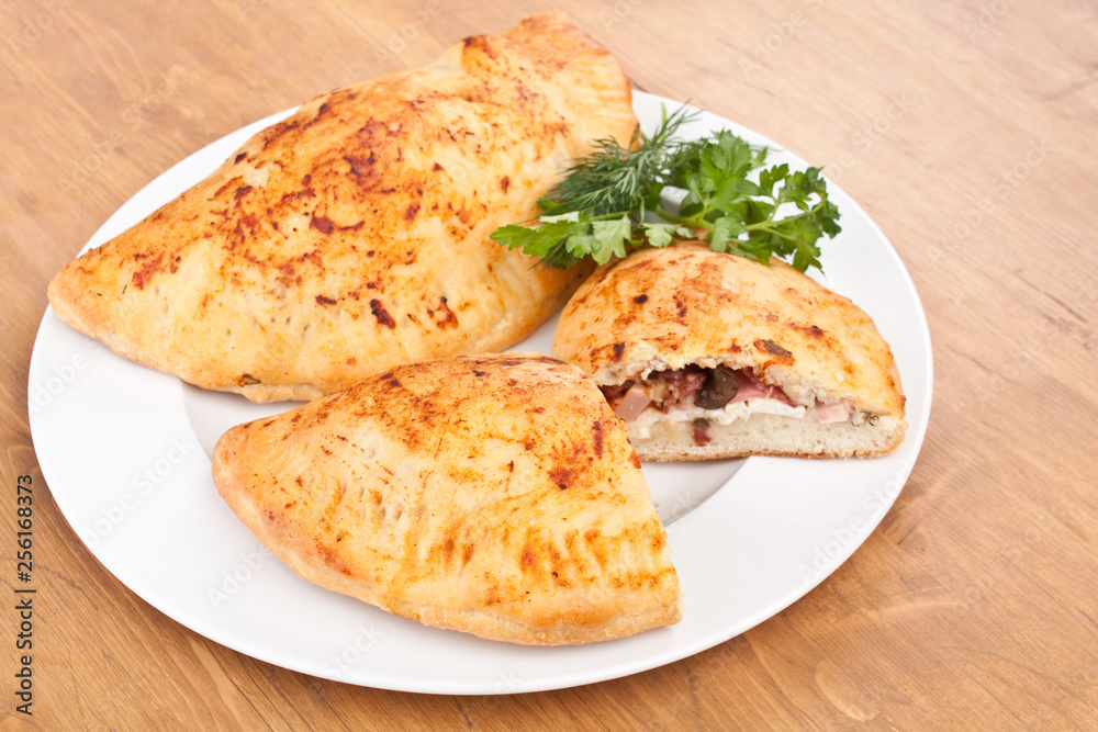 two calzone pizzas stuffed with mushrooms, ham and cheese