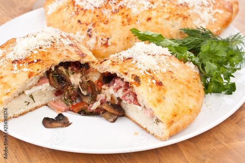 two calzone pizzas stuffed with mushrooms, ham and cheese