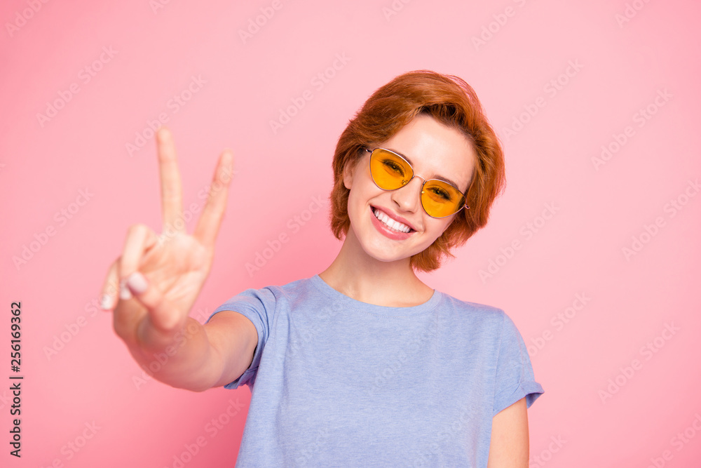 Close-up portrait of her she nice cute charming attractive lovely winsome cheerful optimistic girl wearing casual blue t-shirt yellow glasses giving you v-sign isolated over pink background Close-up portrait of her she nice cute charming attractive lovely winsome cheerful optimistic girl wearing casual blue t-shirt yellow glasses giving you v-sign isolated over pink background