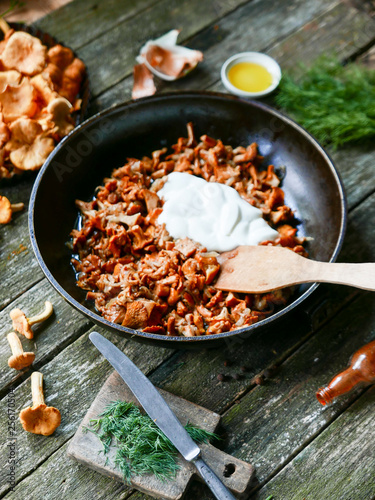 delicious fried chanterelles with sour cream straight from the forest in a pan on a wooden kitchen table