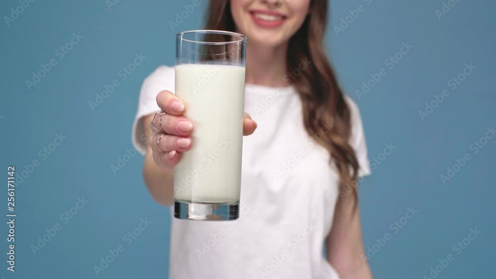 cropped view of girl showing glass of milk at camera and smiling isolated on blue cropped view of girl showing glass of milk at camera and smiling isolated on blue