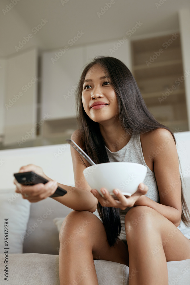 Woman watching television, having breakfast at home in morning Woman watching television, having breakfast at home in morning