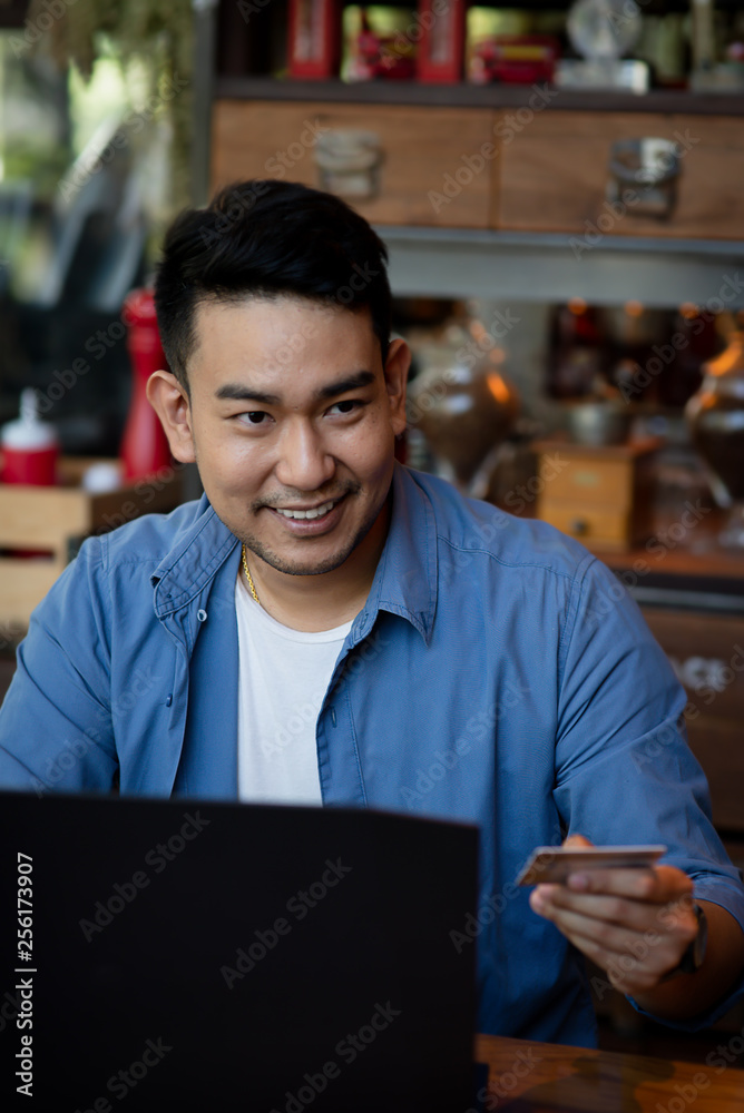 Fototapeta premium Making online bank transfer, man holds a credit card while entering data in laptop