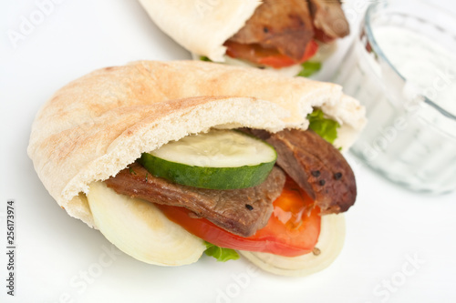 Two halves of pita bread sandwich with meat and vegetables