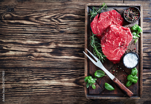 raw beef steaks on a brown cutting board