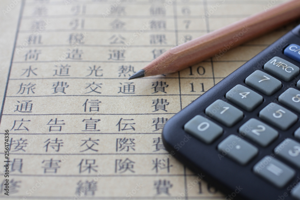 紙に書いた税金や所得や経費と計算機と鉛筆 紙に書いた税金や所得や経費と計算機と鉛筆