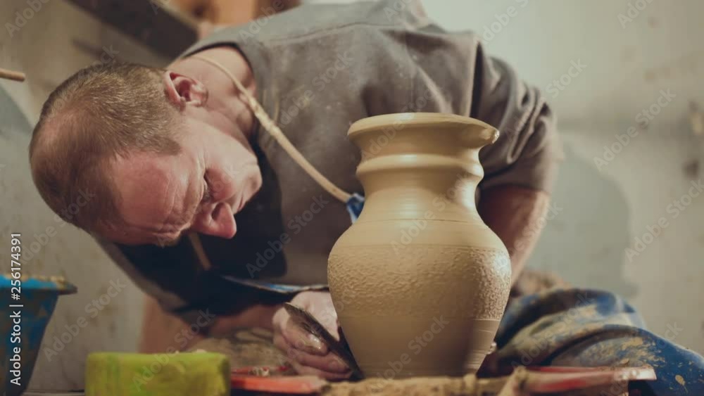 The potter making shape on clay pitcher, using tool for grind The potter making shape on clay pitcher, using tool for grind