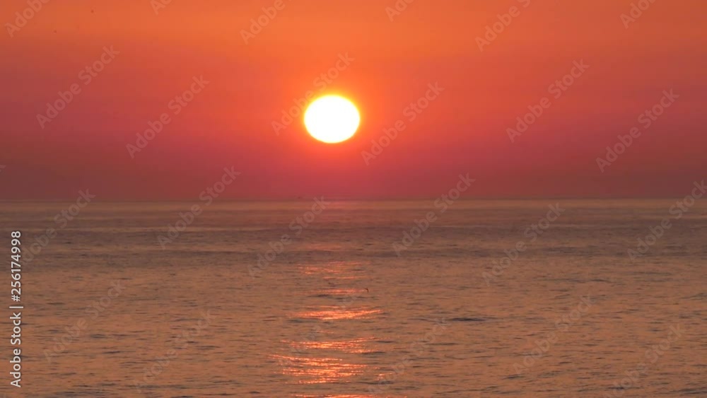 Close up of beautiful sun setting on a calm ocean seen from a cruiseship rocking gently while sailing in calm waters.
