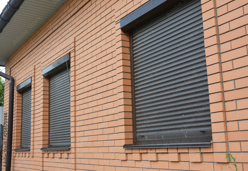 Rolling shutters house windows protection. Brick house with roller shutters on the windows
