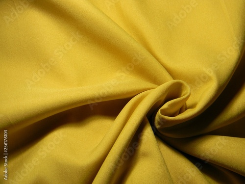 Ochre colored plain cotton wavy fabric. Texture, background. template. Lightweight fabric for curtains or bed linen. Poplin, coarse calico, staple, satin, chintz. Folds. Textile. Material. Mustard