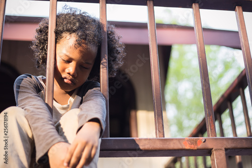 фотографія Little boy sitting behind the fence