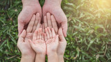 Close up open hands of man and woman and kid with palm up isolated on green grass background. Family together helping green environment protection harmony community and caring concept