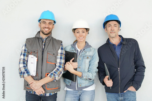 Mixed construction team smiling at camera on grey background