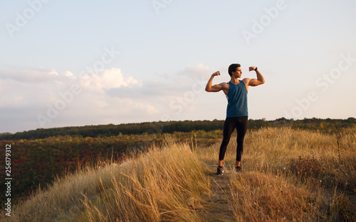 Portrait profile of a athlete, muscular, fit, abs, sportive young man doing stretching exercises with hands, isolated on a beautiful landscape background. Copy space.