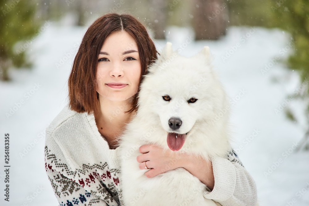 Girl in the winter forest walking with a dog. Snow is falling Girl in the winter forest walking with a dog. Snow is falling