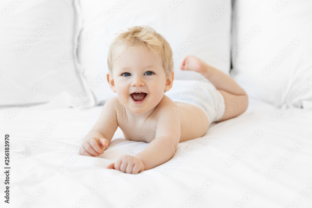 Happy baby boy lying on white bed wearing diaper Happy baby boy lying on white bed wearing diaper