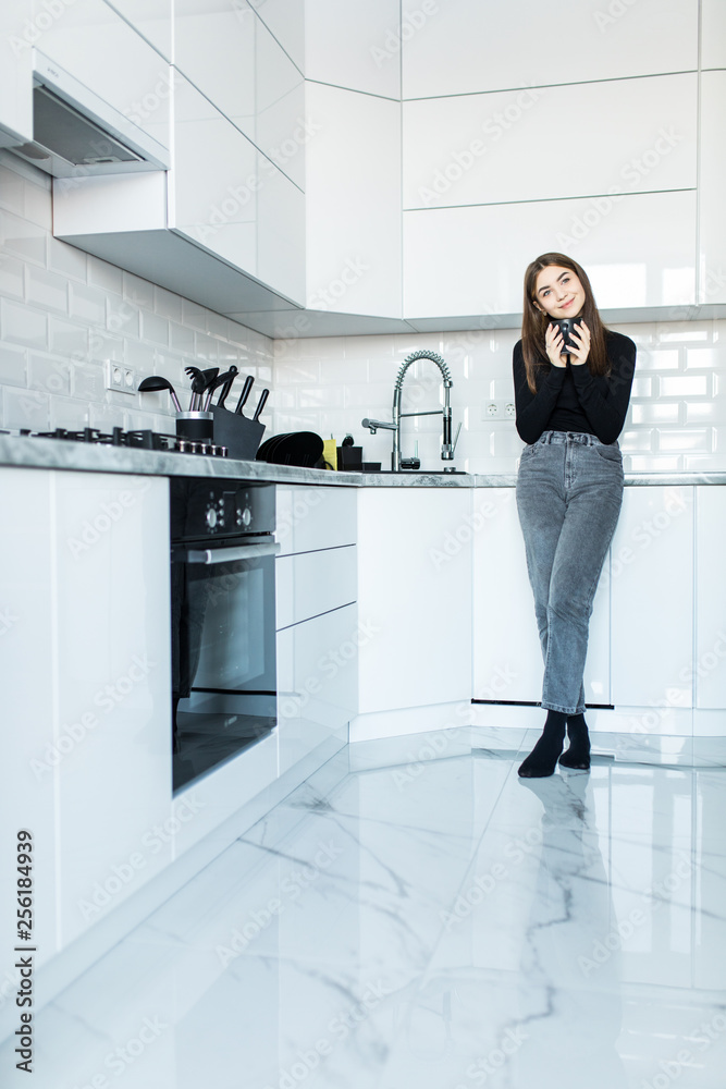 Young happy woman drinking coffee on the kitchen in the morning. Young happy woman drinking coffee on the kitchen in the morning.
