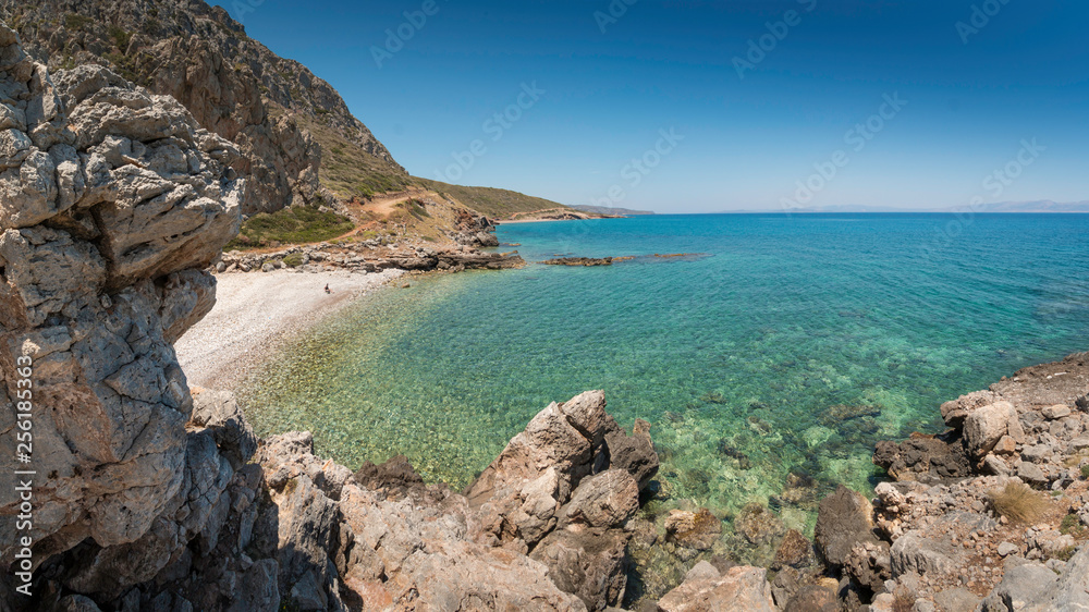 Lonely bay of Kakia Langada with a transparant green sea under a blue sky and rocks in the foreground on the island Kythira, Greece