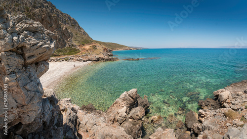 Lonely bay of Kakia Langada with a transparant green sea under a blue sky and rocks in the foreground on the island Kythira, Greece