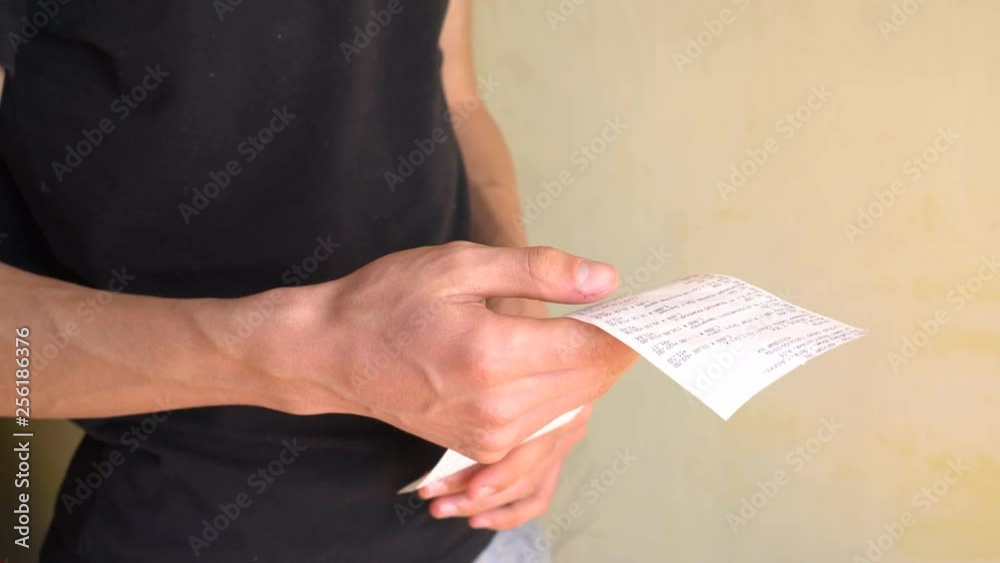 A man keeps track of expenses. A receipt from a supermarket. Frugal Living. Control of Personal Finances A man keeps track of expenses. A receipt from a supermarket. Frugal Living. Control of Personal Finances