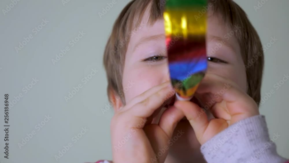 A happy smiling boy with festive tongue-whistle. Portrait of caucasian boy with brown eyes. Happy child's face whistling on clown's whistle. Positive emotions concept. Birthday party eve. A happy smiling boy with festive tongue-whistle. Portrait of caucasian boy with brown eyes. Happy child's face whistling on clown's whistle. Positive emotions concept. Birthday party eve.