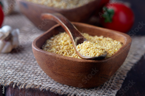 Uncooked raw bulgur wheat grains in wooden bowl