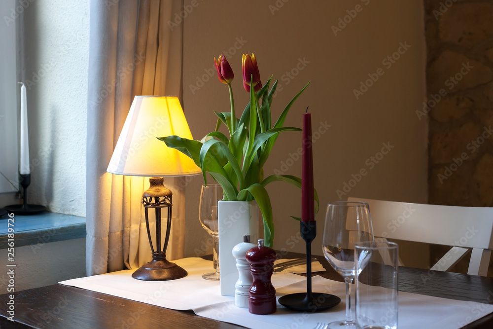 Dining wooden table with white tablecloth, tulips bouquet and glasses Dining wooden table with white tablecloth, tulips bouquet and glasses
