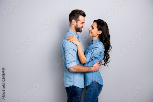 Affection. Profile side view photo of handsome casual spouses looking into eyes satisfied delighted enjoying society dressed in blue denim shirts isolated over argent background