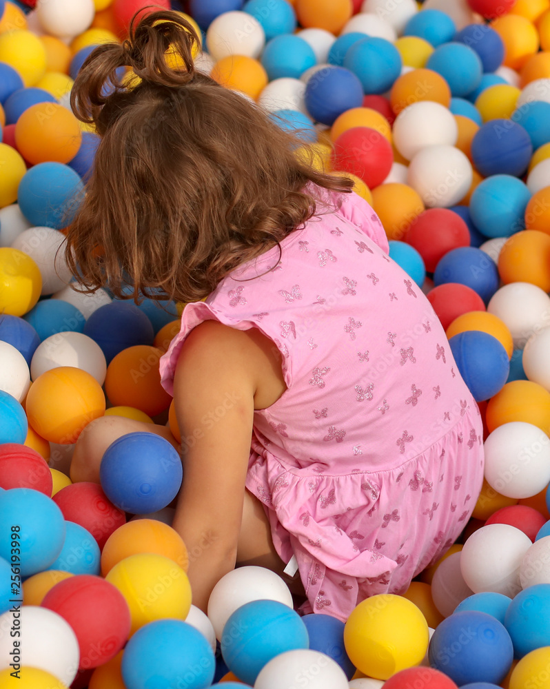 Obraz premium Girl playing in colorful balls on the attraction