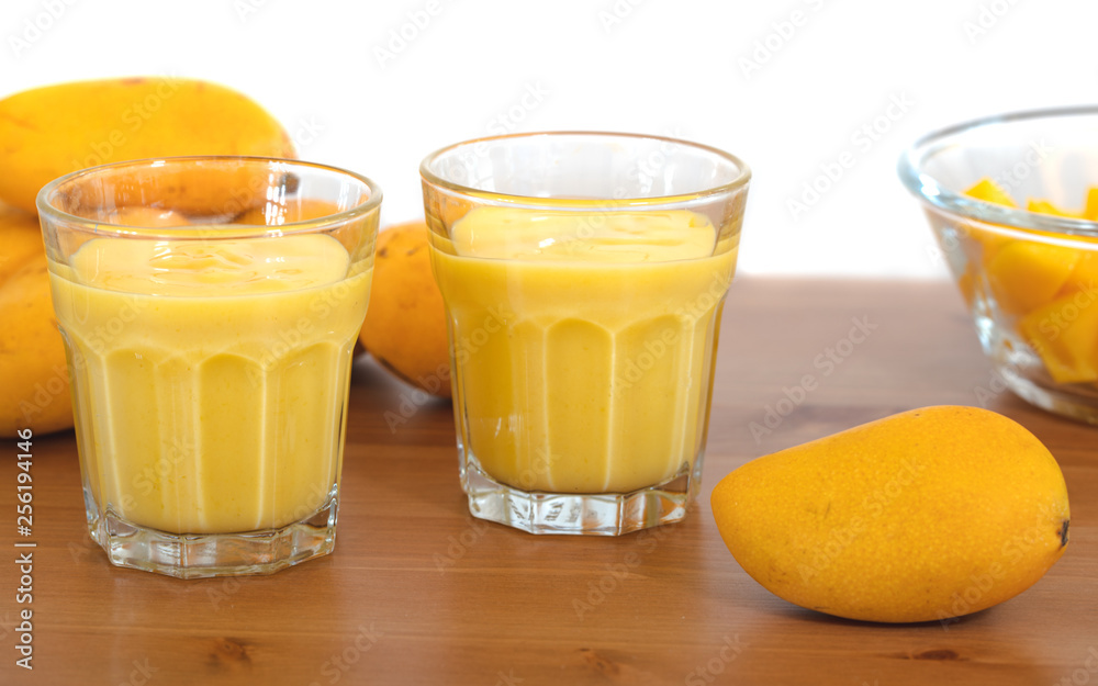 Mango milkshake in glass made with yellow baby Mangos with white background