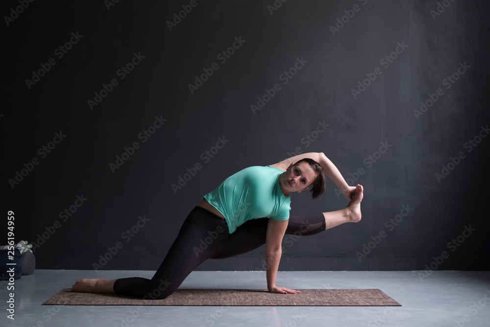 Young woman wearing sportswear practicing yoga in studio,natural light.