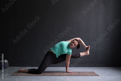 Young woman wearing sportswear practicing yoga in studio,natural light.