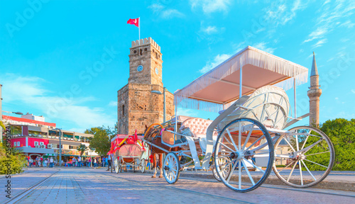 A traditional phaeton is waiting for customers by a Antalya clock tower at Republic Square - Antalya , Turkey photo