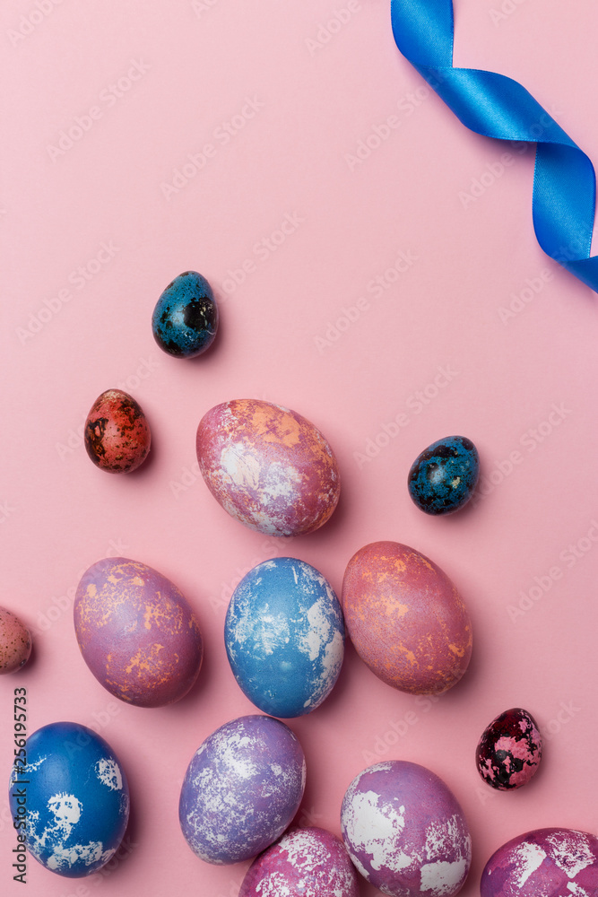 Holiday Easter eggs with white and blue ribbon on pink background