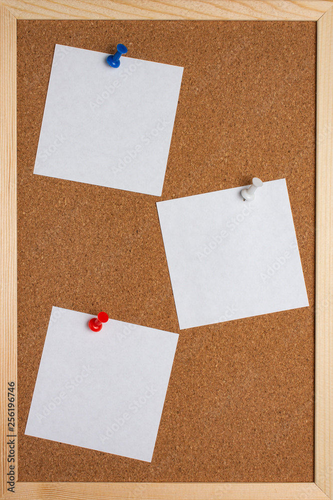 Fototapeta premium Cork board with pinned colored pins and white note sheets