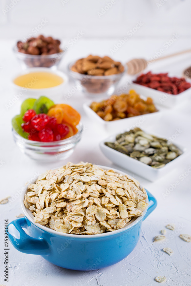 Oat flakes in blue bowl and various delicious ingredients for healthy breakfast on the kitchen table. Healthy breakfast concept. Oat flakes in blue bowl and various delicious ingredients for healthy breakfast on the kitchen table. Healthy breakfast concept.