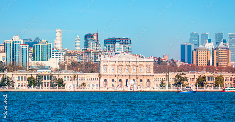 Dolmabahce Palace (Dolmabahce Sarayi) seen from the Bosphorus - Dolmabahce palace against coastal cityscape with modern buildings under cloudy sky istanbul city 