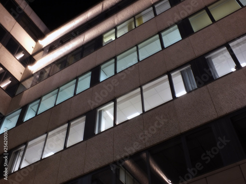 the corner of an office building at night with illuminated walls and lights shining on the exterior facade