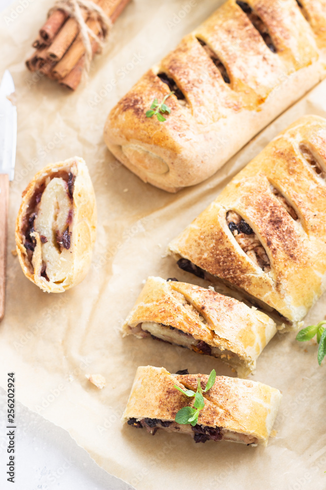 Traditional apple strudel with raisin and cinnamon on grey concrete background. Copy space. Traditional apple strudel with raisin and cinnamon on grey concrete background. Copy space.