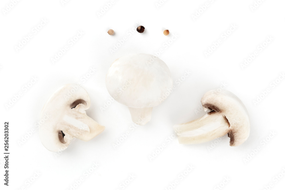 Fototapeta premium Three champignon mushrooms, shot from the top on a white background with pepper, a flatlay composition with copy space