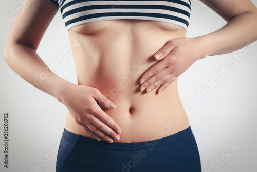 the concept of proper nutrition, women's health. close-up photo of a slender beautiful belly and navel of a woman. She touches the two palms of her hands to her waist. On white background