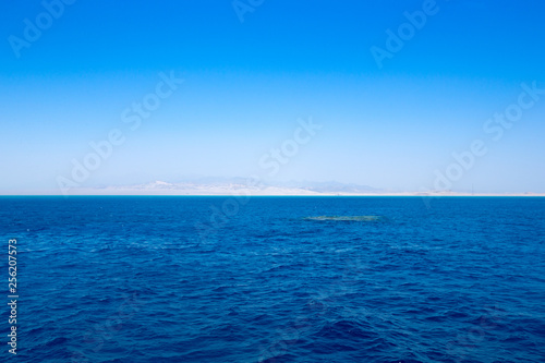 blue sky over calm sea with sunlight reflection