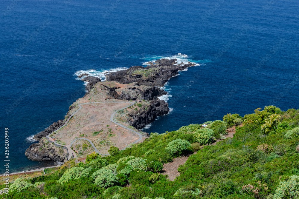 El Sauzal volcanic coastline, stone path and green vegetation, with blue Atlantic ocean, Tenerife, Canary islands, Spain