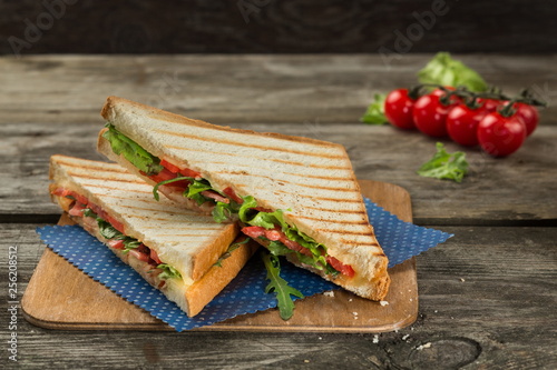 Vegetarian clun sandvich with tomato, cheese ruccola and green salad on the wooden background photo