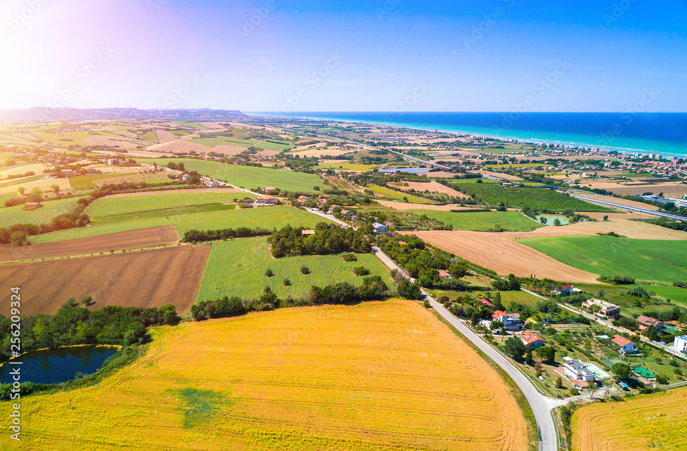aerial italian countryside agricultural landscape with sea in the distance on a sunny day during summer