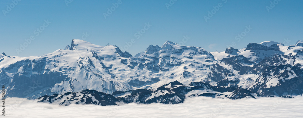 Switzerland, scenic panoramic view on snow Alps peaks above white clouds