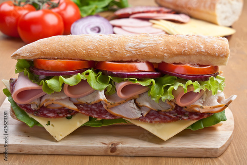 long subway baguette sandwich with meat, vegetables and cheese