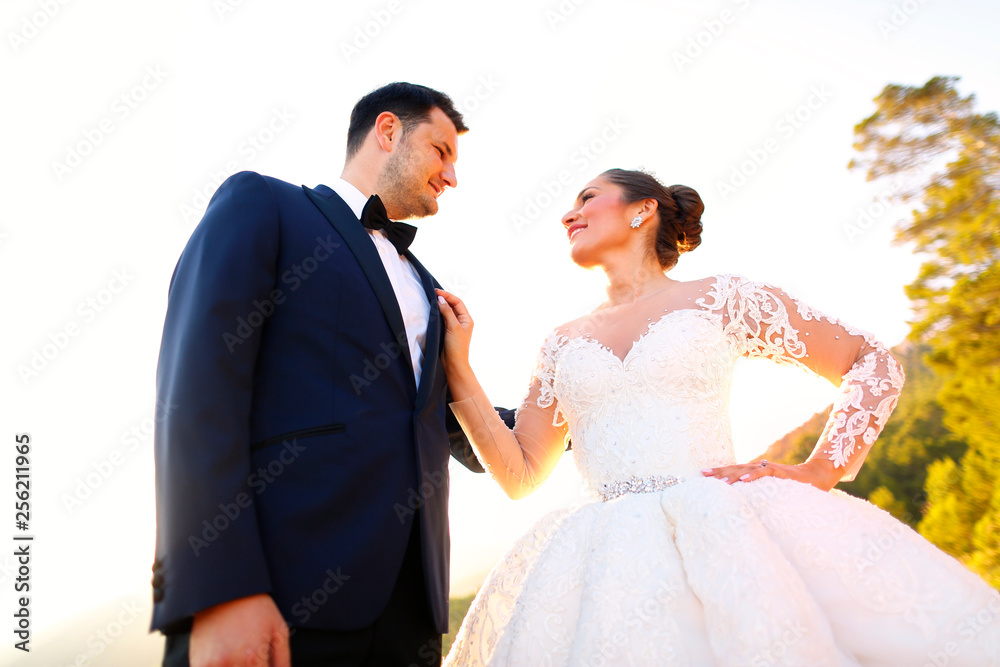 Beautiful wedding couple kissing in the sun near road and trees