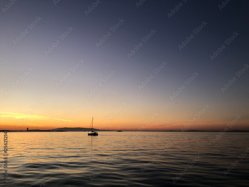 Sailing boat hanging in the middle of the sea after sunset.